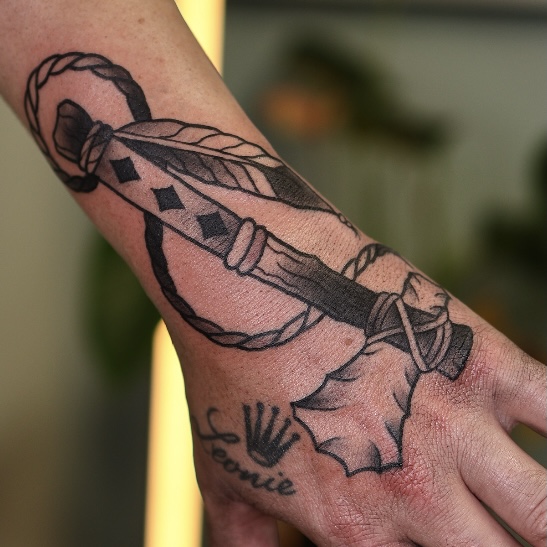 Schwarzes Dolch-Tattoo am Handgelenk