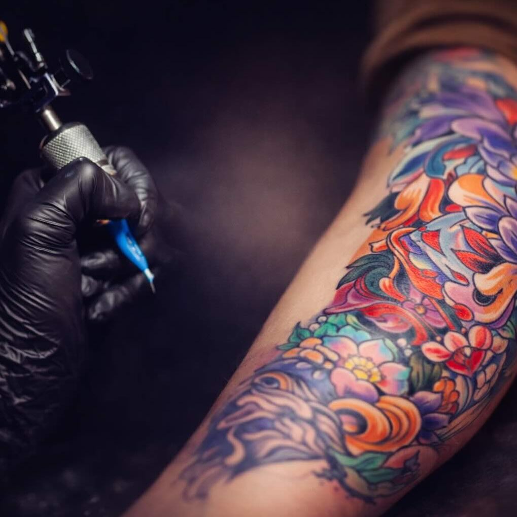 Tätowieren eines farbigen Tattoo-Motivs am Arm