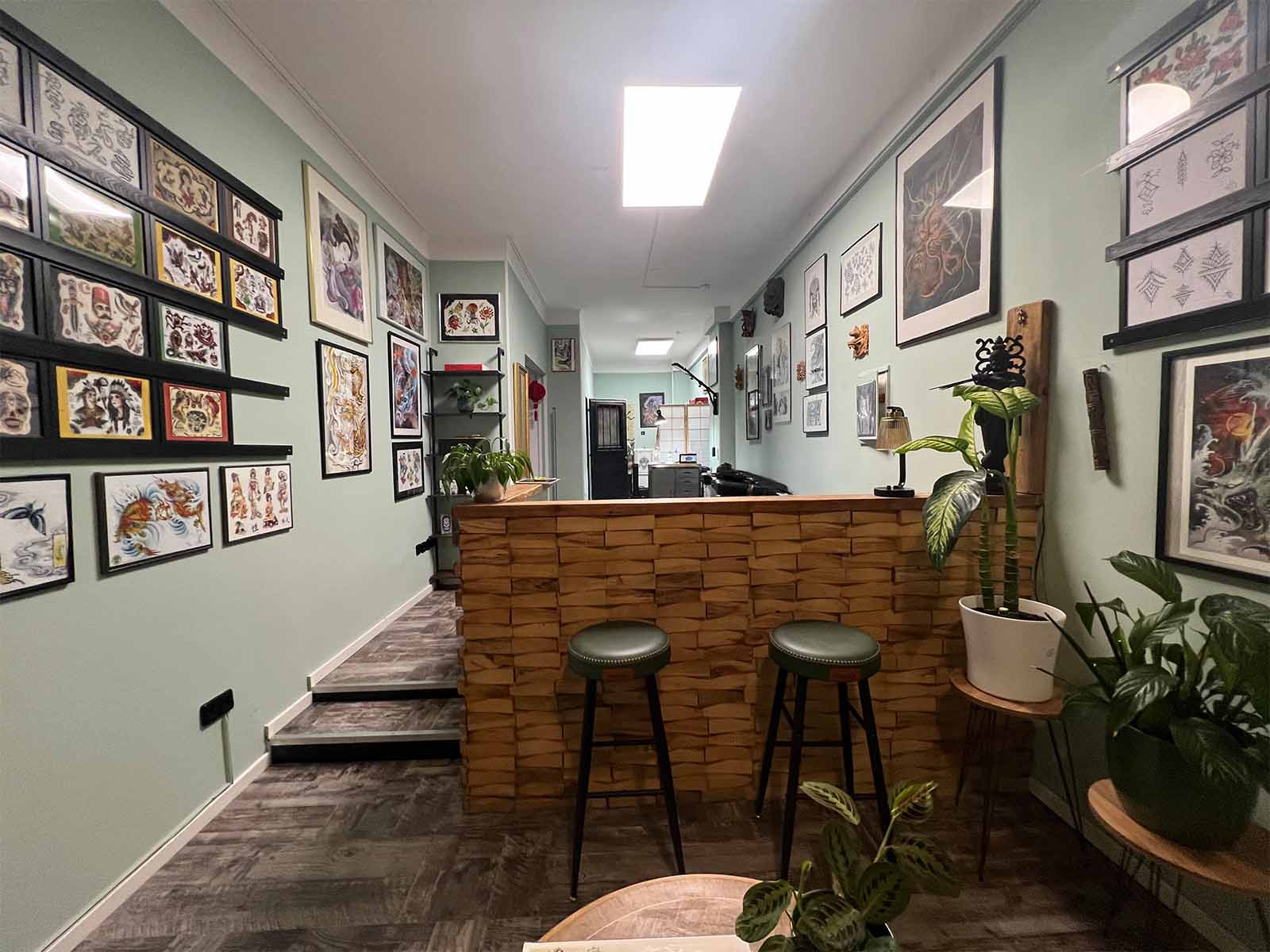 Innenansicht des Electric Eel Tattoo Studios mit Empfangsbereich und Tattoo-Motiven an den Wänden